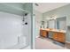 Bright bathroom featuring a white tiled shower and double vanity with wood cabinets and neutral tile flooring at 13354 Blytheville Ave, Port Charlotte, FL 33981