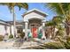 Charming home entrance featuring a vibrant coral door, inviting chairs, and lush landscaping at 13354 Blytheville Ave, Port Charlotte, FL 33981