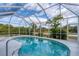 Screened in swimming pool with tropical landscaping, white pool deck, and sunny skies at 13354 Blytheville Ave, Port Charlotte, FL 33981