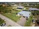 Aerial view of the property shows lush landscaping, screened lanai, and metal roof in a neighborhood setting at 15691 Meacham Cir, Port Charlotte, FL 33981