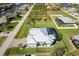 Aerial view of a modern home with screened-in pool, large lawn, and metal roof in a coastal community at 15691 Meacham Cir, Port Charlotte, FL 33981
