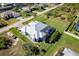 Aerial view of a modern home with screened-in pool, large lawn, and metal roof in a coastal community at 15691 Meacham Cir, Port Charlotte, FL 33981