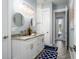 Stylish bathroom with double vanity, round mirrors, modern lighting and blue accent rugs at 15691 Meacham Cir, Port Charlotte, FL 33981