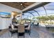 Covered outdoor dining area with a round table, chairs, TV, ceiling fan, and a view of the pool and backyard at 15691 Meacham Cir, Port Charlotte, FL 33981