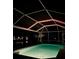 Screened pool glows green at night with pond and landscape views at 170 Long Meadow Ln, Rotonda West, FL 33947