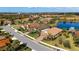 Aerial view of a charming home featuring a red-tile roof, a well-maintained lawn, and a nearby lake at 209 Malina Ct, Nokomis, FL 34275