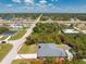 This aerial view shows a corner lot home with a detached garage and a long driveway near a commercial area at 11453 Oceanspray Blvd, Englewood, FL 34224