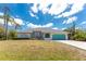 Inviting single-story home with a manicured lawn and a bright turquoise garage door at 11453 Oceanspray Blvd, Englewood, FL 34224