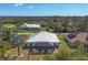 Aerial view of a home with a screened pool, lush landscaping, and a metal roof at 12028 Newgate Ave, Port Charlotte, FL 33981