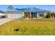 Charming single-story home featuring a large front yard, two-car garage, and light green exterior at 12028 Newgate Ave, Port Charlotte, FL 33981