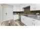 Galley kitchen featuring white cabinets, stainless steel appliances, and wood-look flooring at 1313 Buereau Rd, Englewood, FL 34223