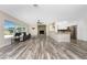 Open-concept living room with stone fireplace, ceiling fan, kitchen, and wood-look flooring at 1313 Buereau Rd, Englewood, FL 34223