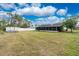 Spacious grassy backyard featuring a white fence, lanai and storage shed at 13360 Foresman Blvd, Port Charlotte, FL 33981