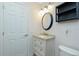 Bathroom showcasing a granite countertop, round mirror, modern lighting, and ample storage at 13360 Foresman Blvd, Port Charlotte, FL 33981