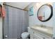 Cozy bathroom with a granite countertop, round mirror, and a shower with tiled wall accents at 13360 Foresman Blvd, Port Charlotte, FL 33981