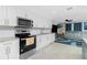 Open kitchen featuring white cabinets, granite countertops, stainless steel appliances, and tile floors at 13360 Foresman Blvd, Port Charlotte, FL 33981