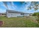 Spacious backyard with mature trees, an outdoor sitting area, and an exterior door at 13559 Martha Ave, Port Charlotte, FL 33981