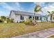Low angle view of a white house with blue trim and mature landscaping at 13559 Martha Ave, Port Charlotte, FL 33981