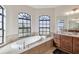 Bright bathroom features a relaxing soaking tub with a view from the three arched transom windows at 15180 Alsask Cir, Port Charlotte, FL 33981