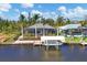 Aerial view of a waterfront home featuring a screened pool, dock, boat lift, and lush tropical landscaping at 15776 Melport Cir, Port Charlotte, FL 33981