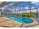 Screened-in pool area with brick pavers, lush landscaping, and waterfront views, perfect for relaxing or entertaining at 15776 Melport Cir, Port Charlotte, FL 33981