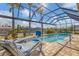Enclosed pool area with lounge chairs, a basketball hoop, and a clear view of the canal at 15776 Melport Cir, Port Charlotte, FL 33981