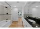 Well-lit bathroom with black granite vanity, white cabinets, and tiled shower-tub at 18 Pebble Beach Road, Rotonda West, FL 33947