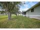 Beautiful home exterior with lush green lawn, mature trees, and a screened patio, ideal for outdoor enjoyment at 18 Pebble Beach Road, Rotonda West, FL 33947