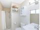 Bright bathroom with shower, white toilet, and convenient shelving for storing towels and toiletries at 18970 Mcgrath Cir, Port Charlotte, FL 33948