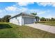 Neutral home featuring a two car garage, an expansive driveway, and a lush green yard at 194 Sunset Rd, Rotonda West, FL 33947