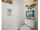 Charming half bathroom with palm tree towel, colorful wall decor, and a white toilet at 194 Sunset Rd, Rotonda West, FL 33947