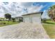 A well-maintained home with a spacious driveway leading to a garage with a lush lawn and palm trees at 237 W Pine Valley Ln, Rotonda West, FL 33947