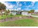 Charming single Gathering home featuring a lush green lawn and complemented by swaying palm trees at 237 W Pine Valley Ln, Rotonda West, FL 33947