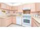 Kitchen view featuring white appliances, double sink, and peach-colored cabinets at 2948 Briant St, North Port, FL 34287