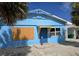 Quaint single-story blue house with boarded window and covered entry under clear blue skies at 40 Sand Dollar Ln, Englewood, FL 34223