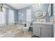 Charming bathroom with blue walls, tub, updated vanity, and decorative mirror at 5703 Holiday Park Blvd, North Port, FL 34287