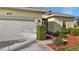 Close up view of the attached two-car garage with surrounding landscaped garden beds at 677 Barnacle Ct, Englewood, FL 34223