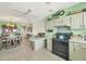 Eat-in kitchen with white cabinetry, updated appliances, an island, and views into the living spaces at 8436 Buttonquail Dr, Englewood, FL 34224