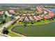 Nice aerial view of neighborhood homes with red tile roofs, lake, and lush green landscaping at 10508 Crooked Creek Dr, Venice, FL 34293