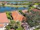 Aerial view of a red-roofed home, with solar panels, a screened pool and lake views at 10508 Crooked Creek Dr, Venice, FL 34293
