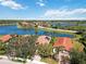Aerial view of red-roofed homes overlooking a scenic lake, each featuring screened-in pools at 10508 Crooked Creek Dr, Venice, FL 34293