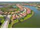 Aerial view of a community with terracotta roofs, a lake, and mature landscaping in a desirable location at 10508 Crooked Creek Dr, Venice, FL 34293