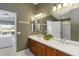 Spacious bathroom featuring double sinks, wood cabinets, large mirror, and connected bedroom and shower room at 10508 Crooked Creek Dr, Venice, FL 34293