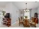 A dining room features a glass table, 6 chairs, a chandelier, and decorations by the window at 10508 Crooked Creek Dr, Venice, FL 34293