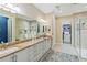 Bathroom featuring double sinks, granite countertops, white cabinetry, and a glass enclosed shower at 10953 Bullrush Dr, Venice, FL 34293