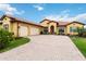 Charming, well-maintained single-story home with a tile roof, lush landscaping, and a brick driveway at 10953 Bullrush Dr, Venice, FL 34293