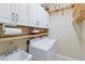 Well-organized laundry room with sink, modern washer, dryer and ample shelving for storage solutions at 10953 Bullrush Dr, Venice, FL 34293