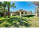 Expansive backyard with a covered patio and mature palm trees providing shade and privacy at 1183 Cedar Ave, Englewood, FL 34223