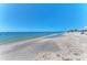 Serene beach scene with clear turquoise water meeting a shell-strewn shoreline under a bright blue sky at 1183 Cedar Ave, Englewood, FL 34223