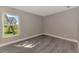 Bright bedroom with a window offering an outside view and modern gray wood-look flooring at 1183 Cedar Ave, Englewood, FL 34223
